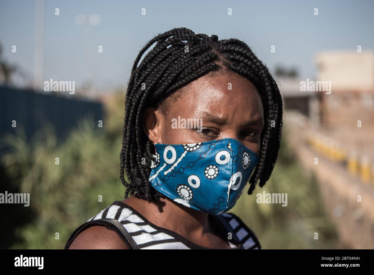 Frau, die eine lokale handgefertigte Gesichtsmaske aus traditionellem afrikanischen Stoff zum Schutz vor Corona-Virus trägt Stockfoto