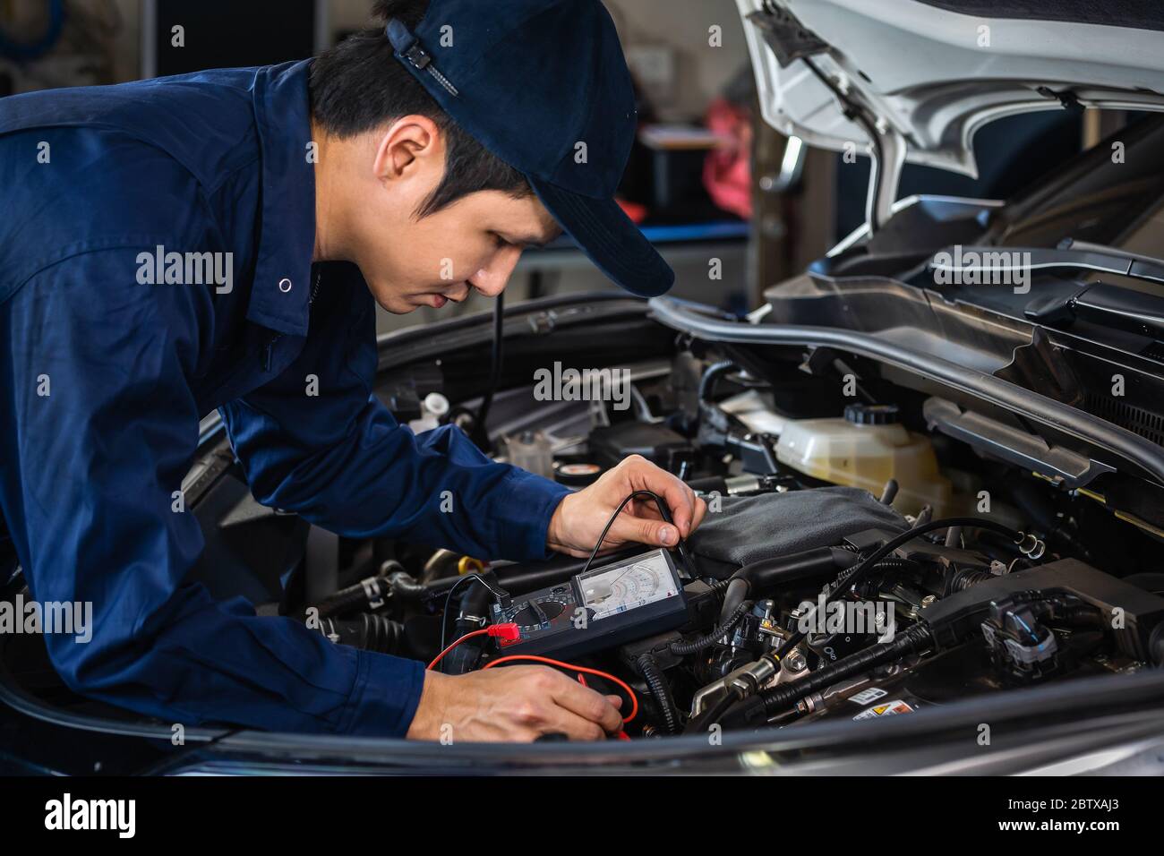 Männliche Mechaniker überprüfen elektrische Verdrahtung Fahrzeugsystem in einem Auto-Service Stockfoto