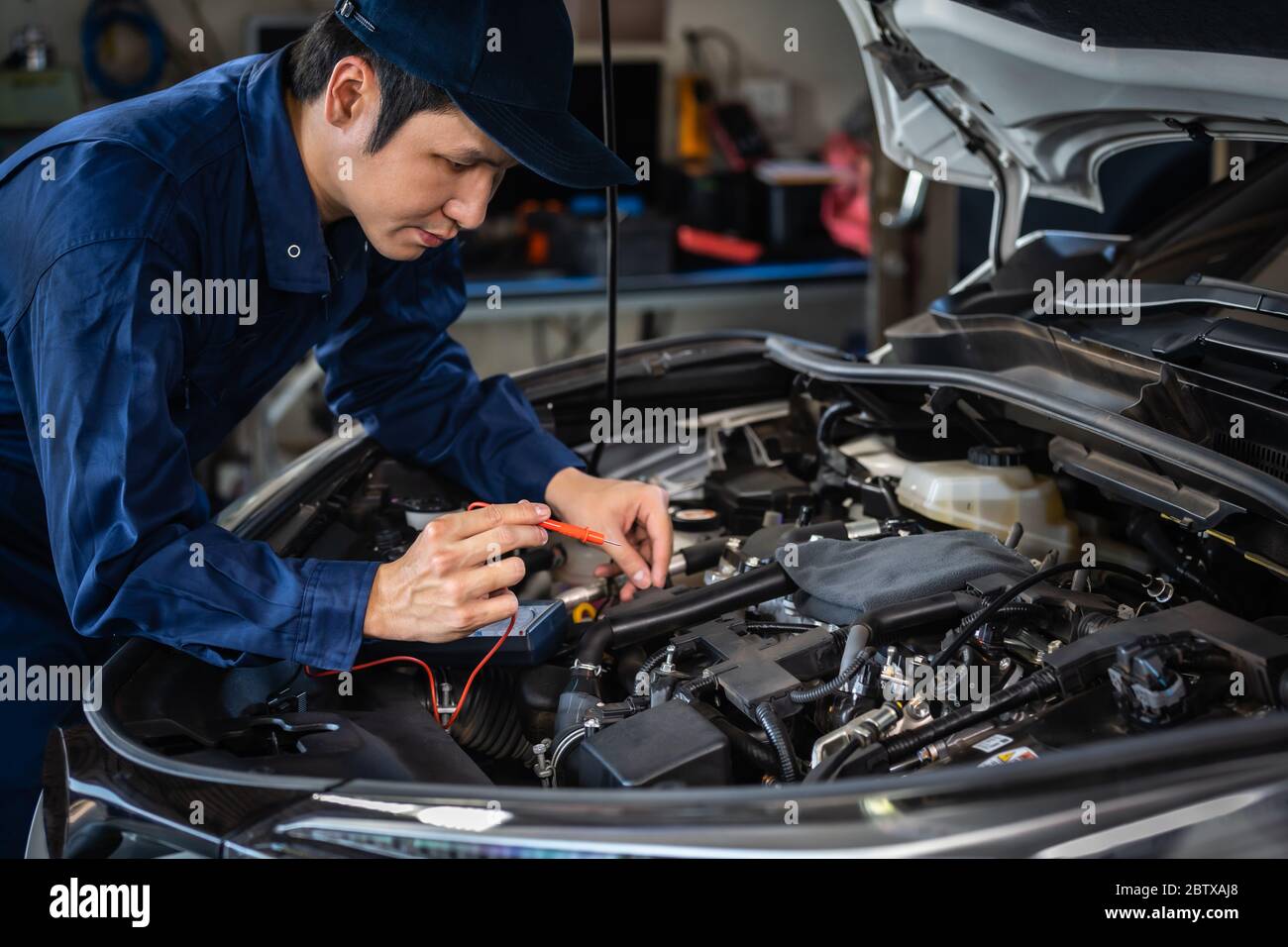 Männliche Mechaniker überprüfen elektrische Verdrahtung Fahrzeugsystem in einem Auto-Service Stockfoto