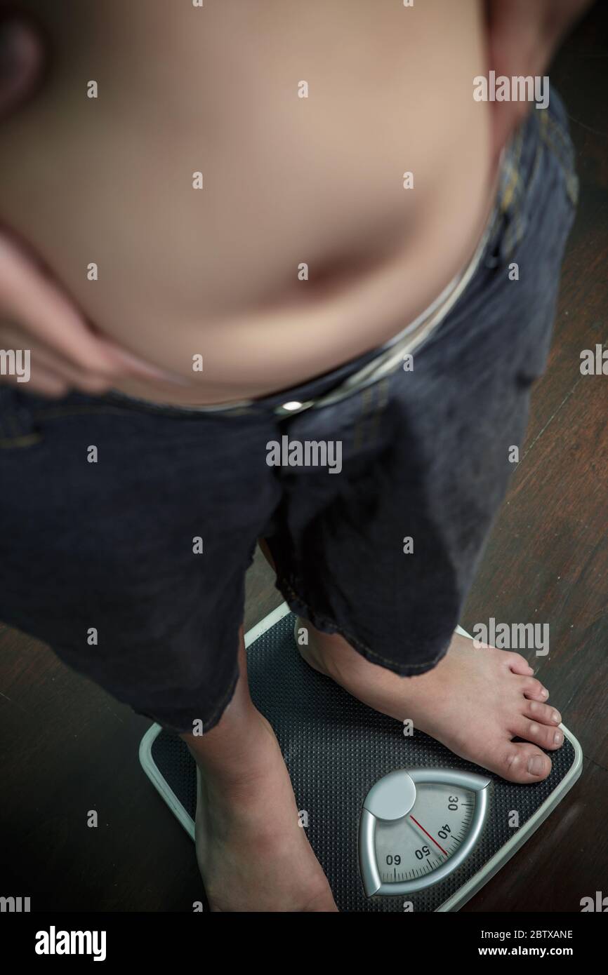Fat Boy misst Gewicht auf der Bodenwaage, gesund und Gewicht verlieren Konzept Stockfoto