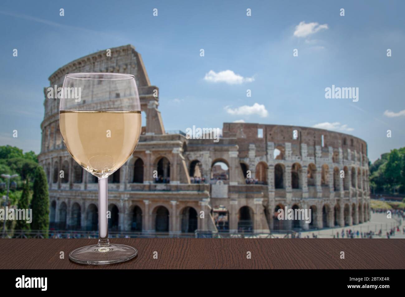Ein Glas Weißwein gegen das Kolosseum in Rom, Italien. Tisch mit Blick auf das römische ovale Amphitheater. Stockfoto
