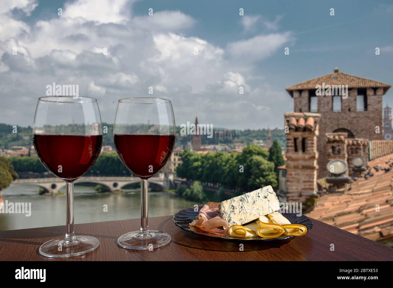 Zwei Gläser Wein mit Wurstwaren-Sortiment auf Sicht von Verona, Italien. Ein Glas Rotwein mit verschiedenen Snacks - Teller mit Schinken, in Scheiben geschnitten, blauer Käse Stockfoto