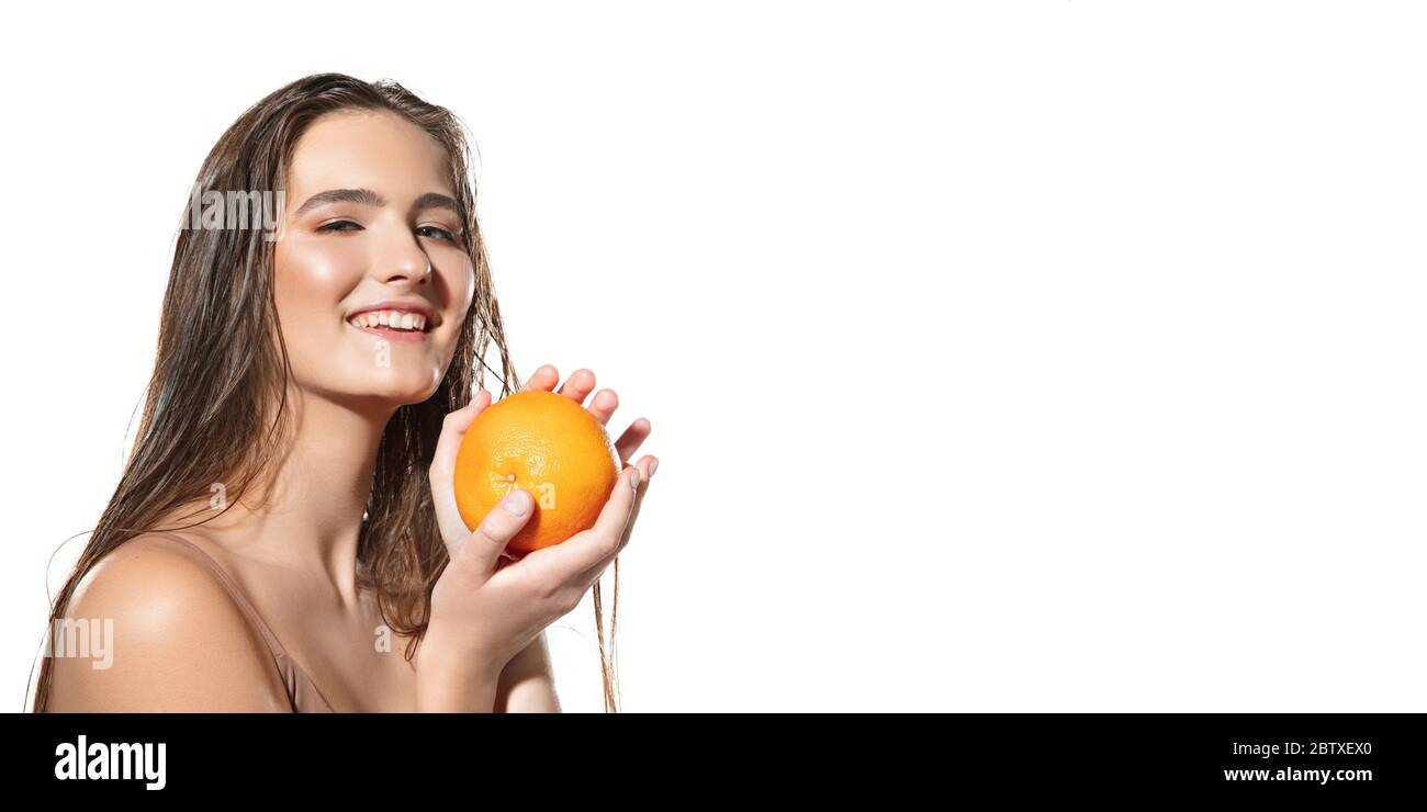Berühren Sie. Nahaufnahme der schönen jungen Frau mit orange auf weißem Hintergrund. Konzept der Kosmetik, Make-up, natürliche und ökologische Behandlung, Hautpflege. Glänzende und gesunde Haut, Gesundheit. Flyer mit Copyspace. Stockfoto