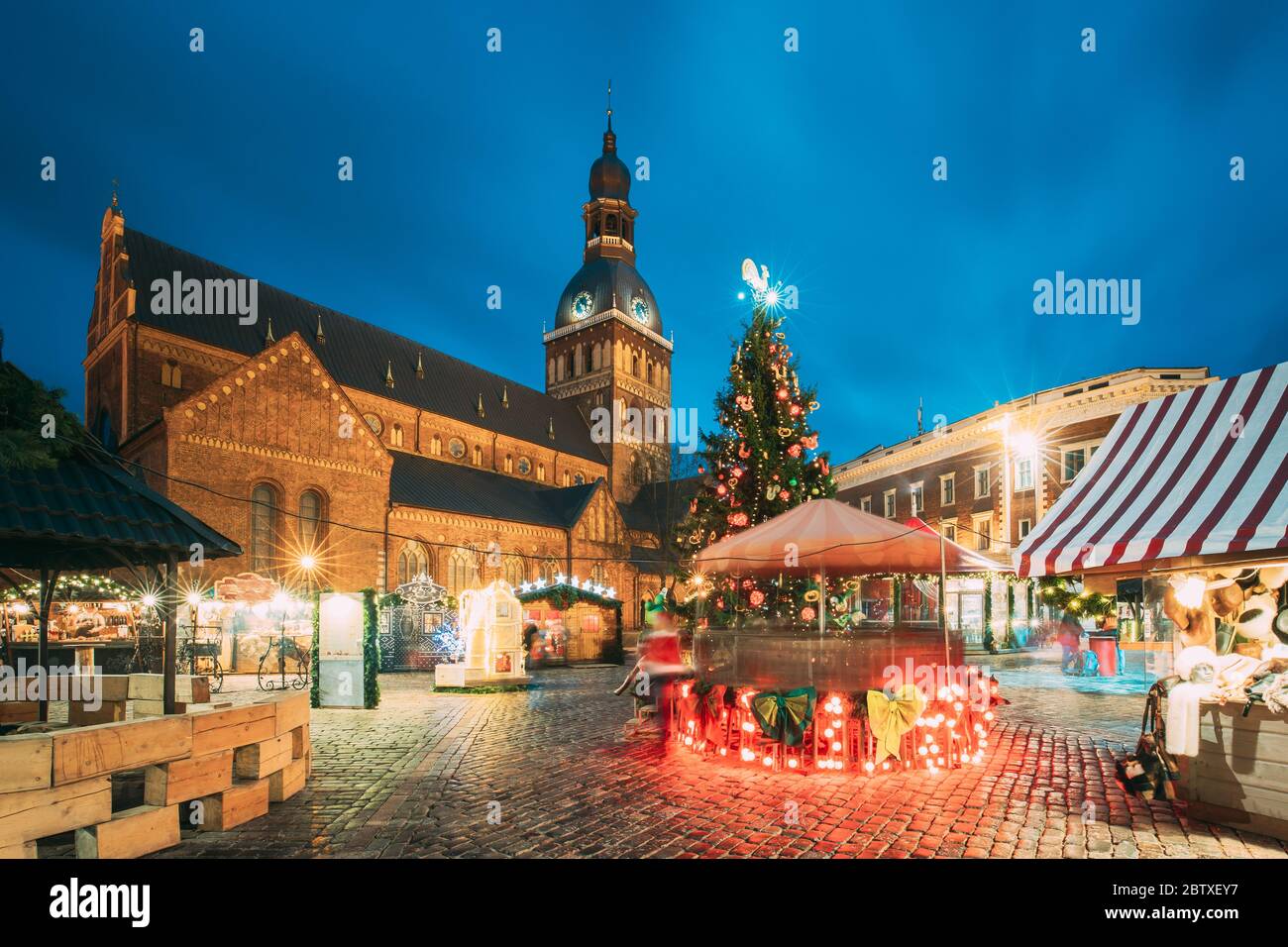 Riga, Lettland. Weihnachtsmarkt Auf Dem Domplatz Mit Der Kathedrale Des Rigaer Doms. Weihnachtsbaum Und Handelshäuser. Berühmte Sehenswürdigkeit Im Winter Abend Nacht In Stockfoto