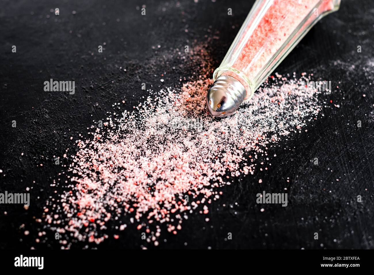 Rosa Salz in einem Glas Vintage Shaker, auf einem dunklen Hintergrund verstreut Stockfoto