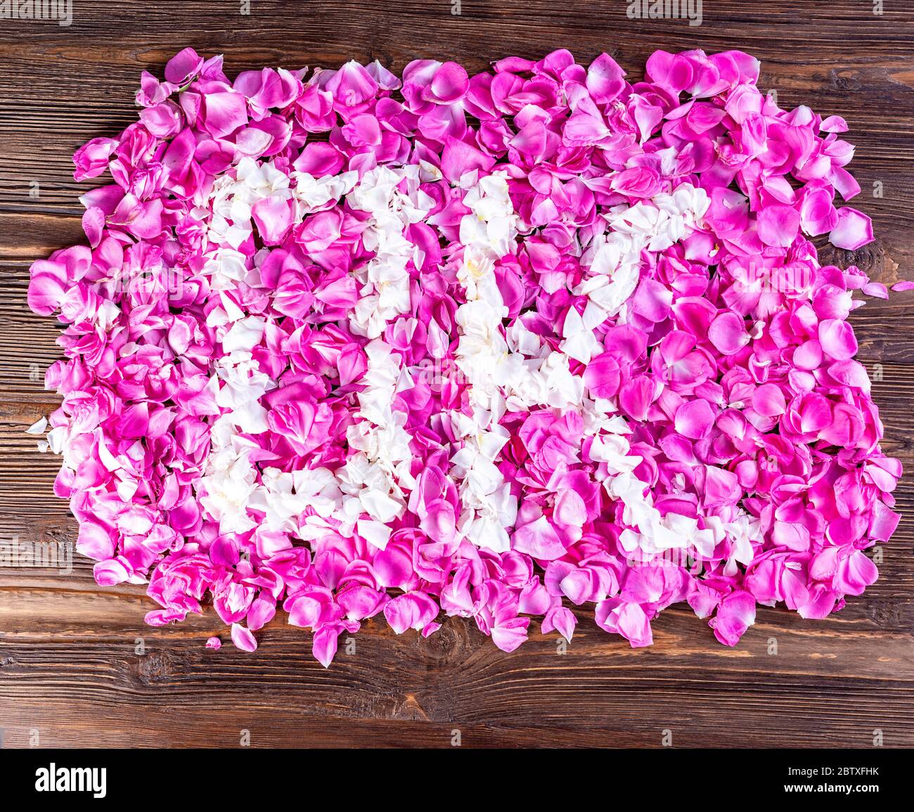 Ein Quadrat aus weißen und rosa Rosenblättern mit stilisiertem OK Wort auf Holzhintergrund Stockfoto