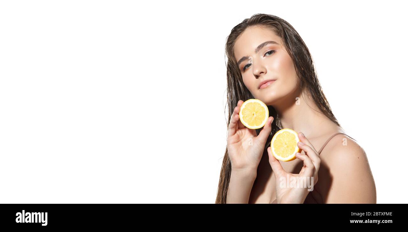 Nahaufnahme der schönen jungen Frau mit Zitronenscheiben auf weißem Hintergrund. Konzept der Kosmetik, Make-up, natürliche und ökologische Behandlung, Hautpflege. Glänzende und gesunde Haut, Gesundheit. Flyer mit Copyspace. Stockfoto