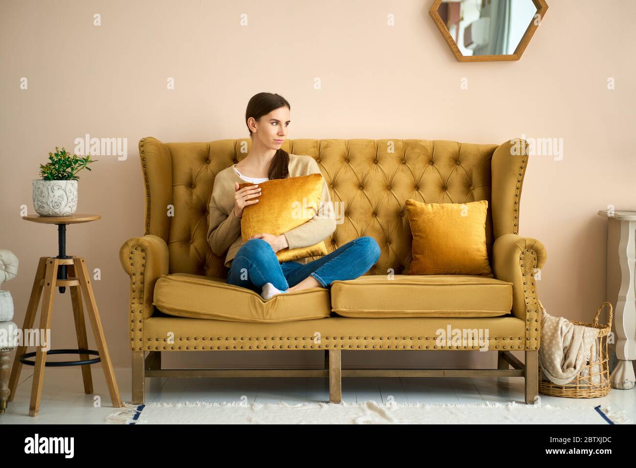 Wochenende mit ruhiger Stimmung. Mädchen auf der Couch, das Fenster im Wohnzimmer und erinnert an angenehme Momente Stockfoto