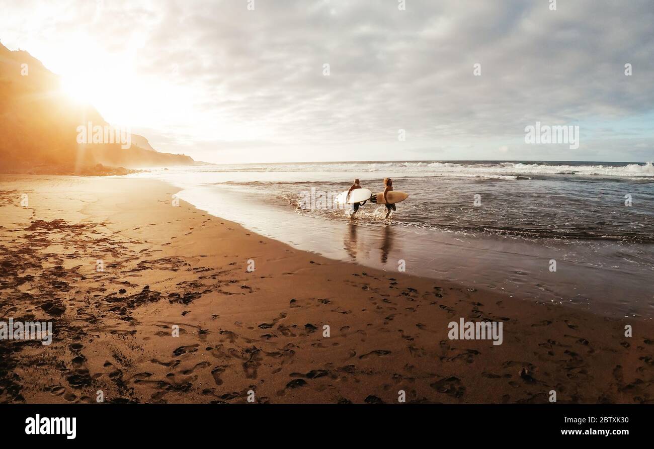 Glückliche Freunde gemeinsam auf dem tropischen Ozean surfen - Sportliche Menschen haben Spaß während des Urlaubs Surf Day - Extreme Sport Lifestyle Konzept Stockfoto