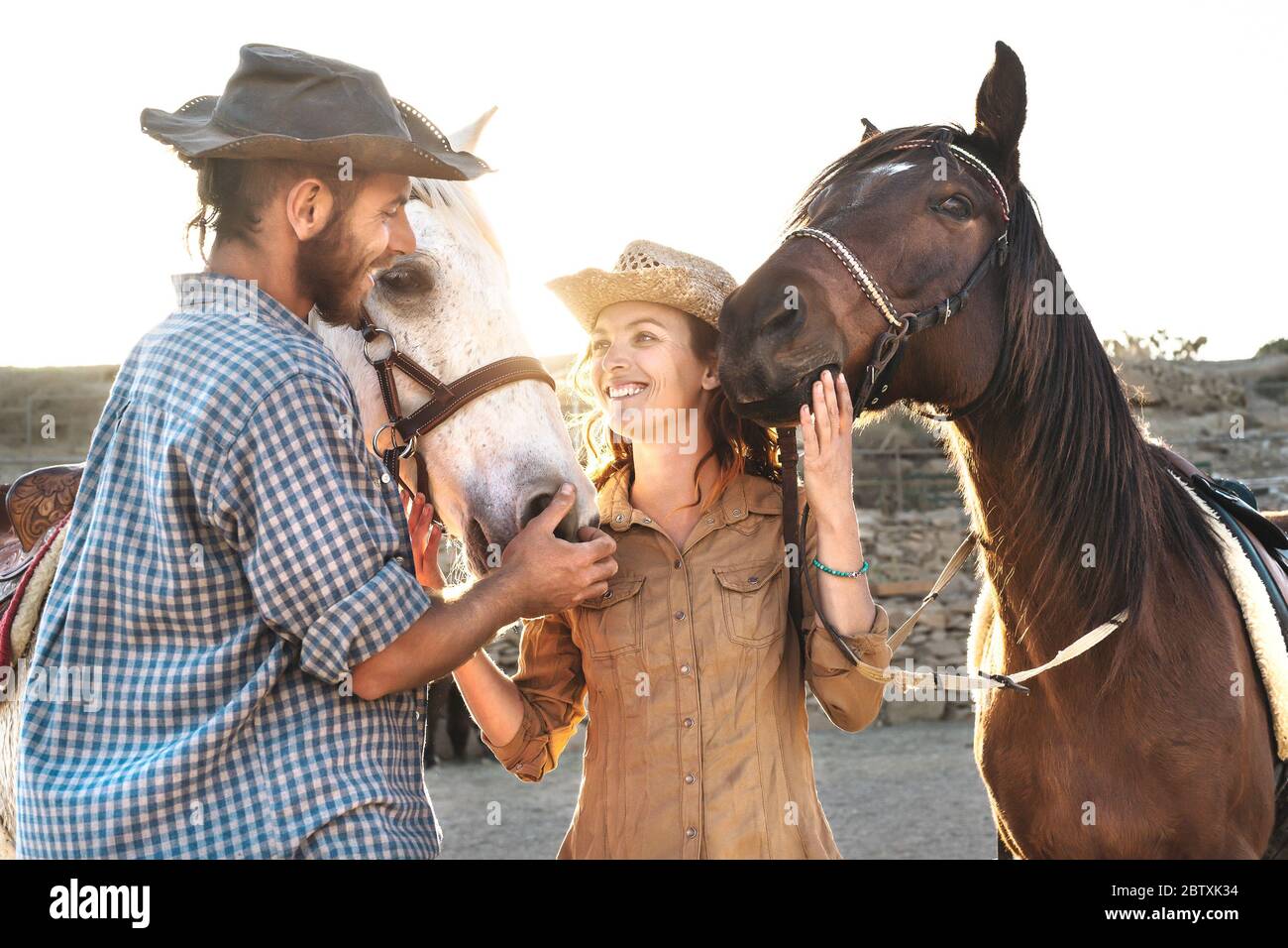 Glückliches Paar Spaß mit Pferden im Stall - Junge Bauern teilen Zeit mit Tieren in Corral Ranch Stockfoto