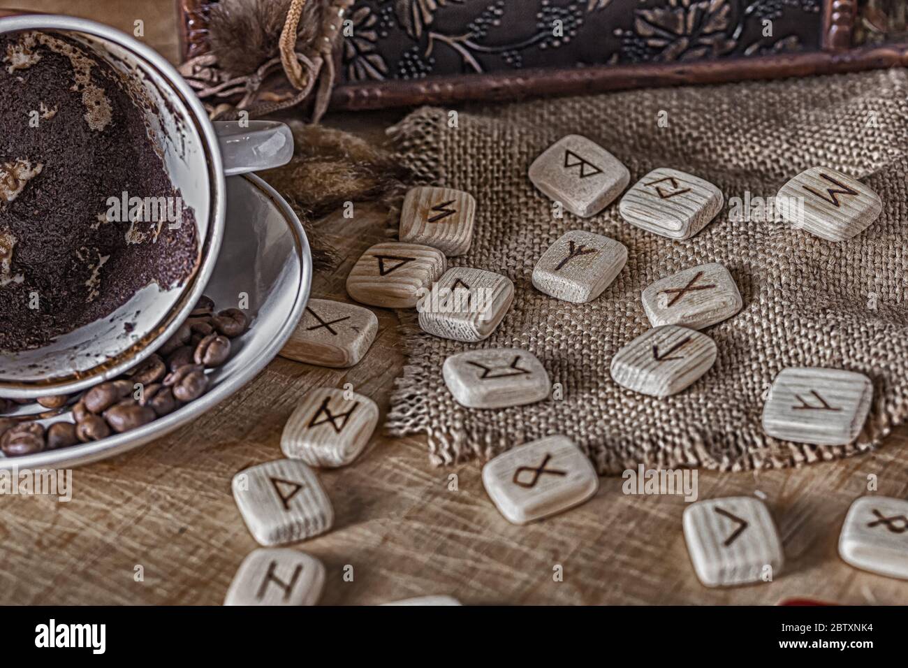 Isoterisches Konzept der Weissagung und Vorhersage. Runen, Kaffeesatz in einer Tasse, Rosenkranz auf einem Tisch vor dem Hintergrund einer alten Brust Stockfoto