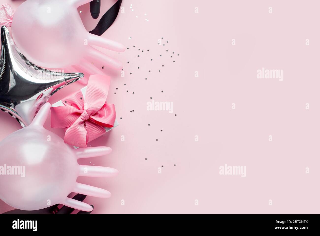 Creative Concept Geschenkbox, Party-Dekor und medizinische Handschuhe als Luftballon auf rosa Hintergrund mit Kopierraum. Luxus-Mode, Shopping Pandemie Verkauf CO Stockfoto
