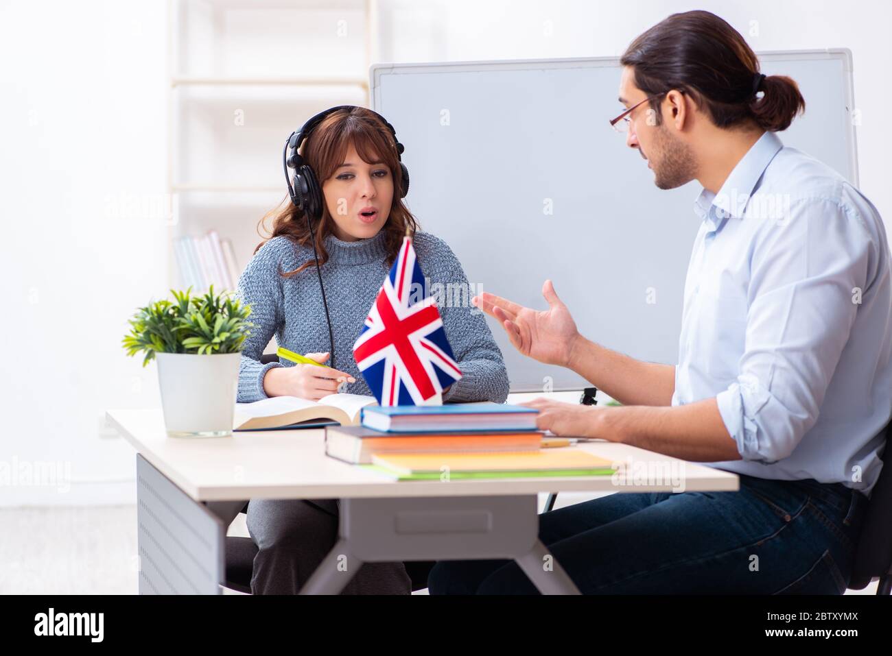 Junger Schüler und männlicher englischlehrer im Klassenzimmer Stockfoto