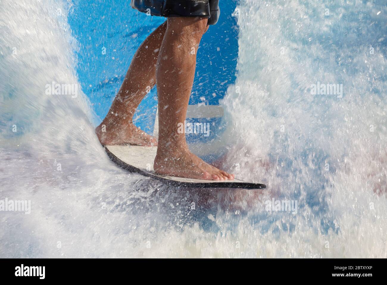 Man nimmt Wake Surf, Reiten ein Surfbrett oder Fußbrett entlang einer Outdoor-Wasserrutsche eingerichtet Stockfoto