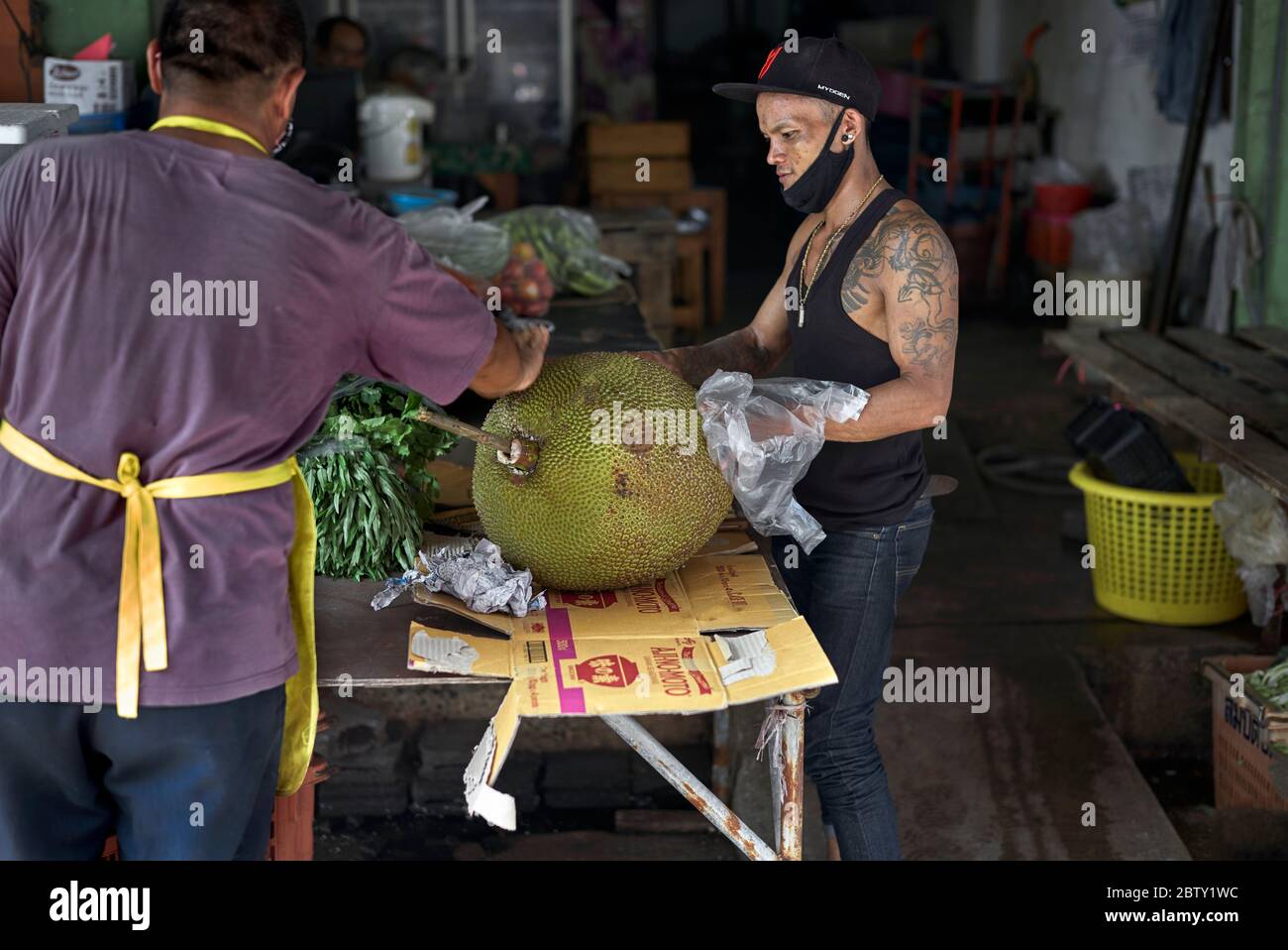 Jackfruit. Markthändler, die eine sehr große Jackfrucht (Artocarpus heterophyllus) inspizieren und bewundern Stockfoto