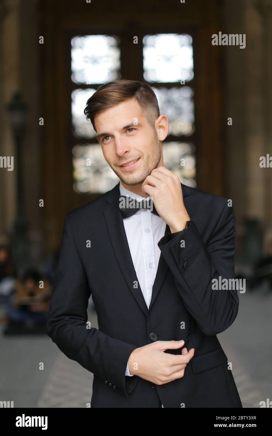 Junger Bräutigam steht und wartet, trägt schwarzen Anzug und Fliege  Stockfotografie - Alamy