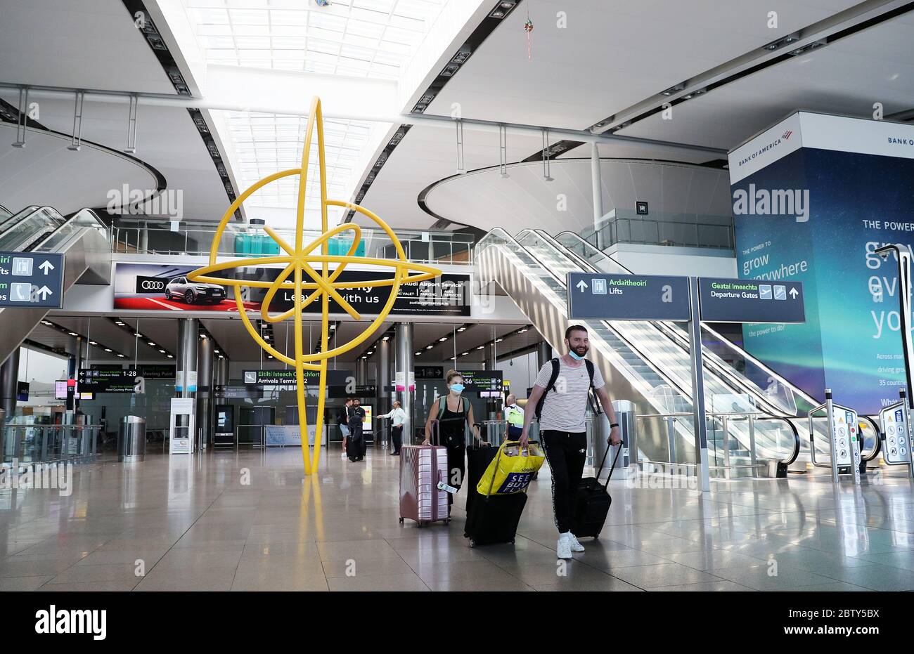 Personen mit Schutzmaske laufen durch Terminal 2 am Flughafen Dublin, da die Anforderung für Personen, die aus Übersee nach Irland kommen, die Behörden zu informieren, wo sie sich selbst isolieren werden, in Kraft getreten ist. Stockfoto
