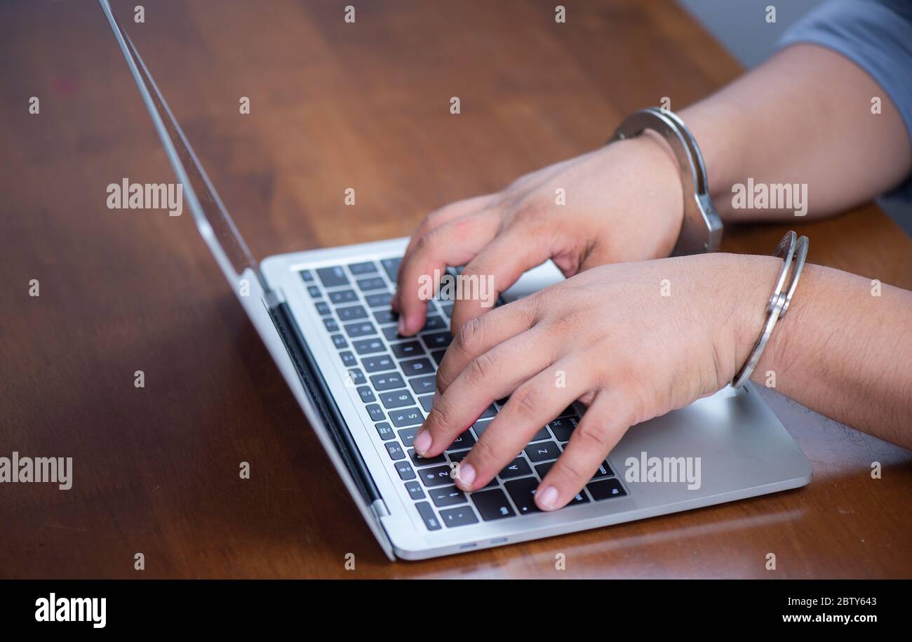Handschellen mit Laptop durch auf der Tastatur des Notebooks sperren, elektronisches Verbrechen Konzept Stockfoto