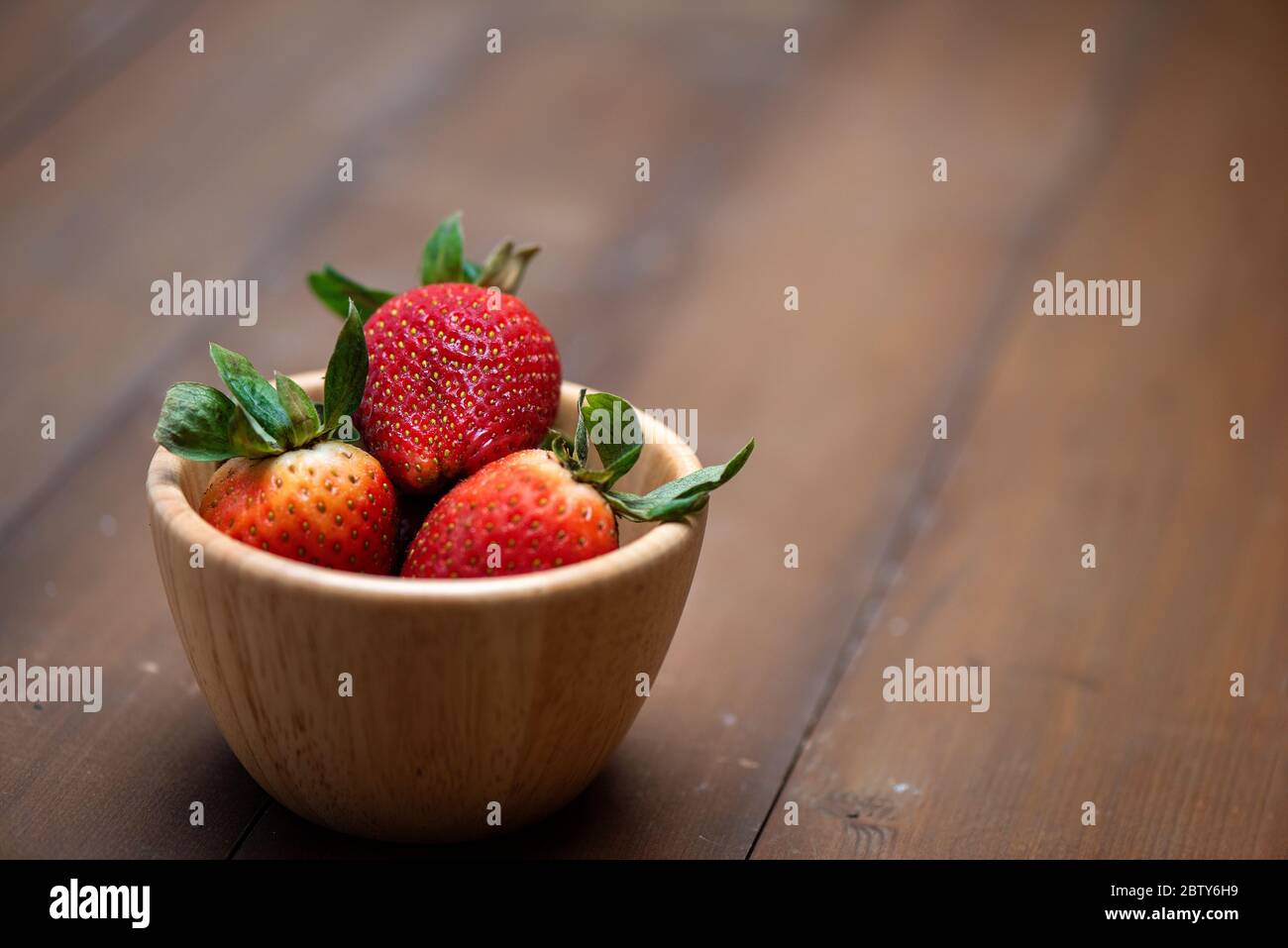 Frische Erdbeeren in eine Schüssel auf hölzernen Hintergrund Stockfoto