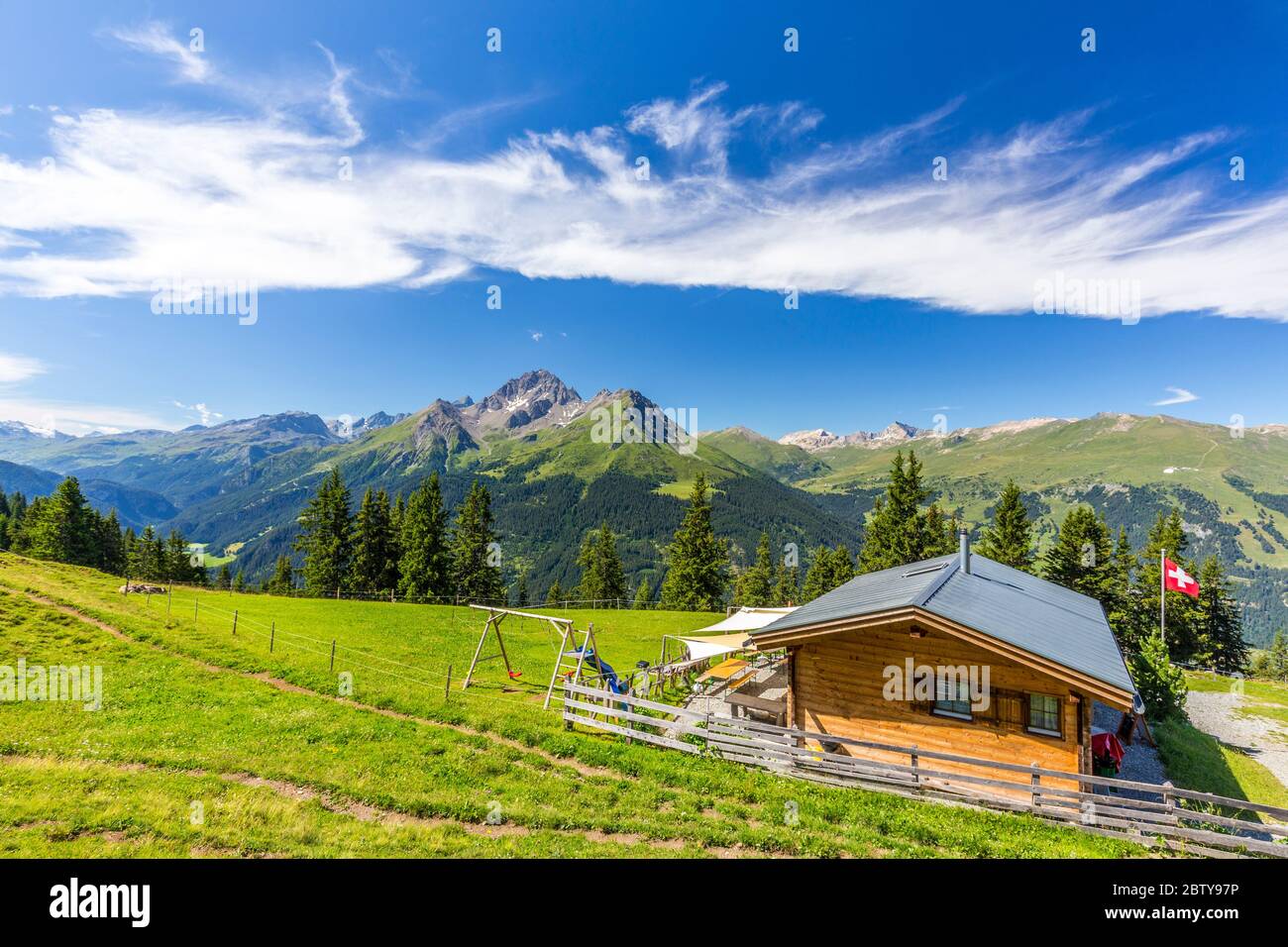 Berghütte mit Schweizer Flagge unter atemberaubenden Wolken, Urses, Surselva, Graubünden, Schweiz, Europa Stockfoto