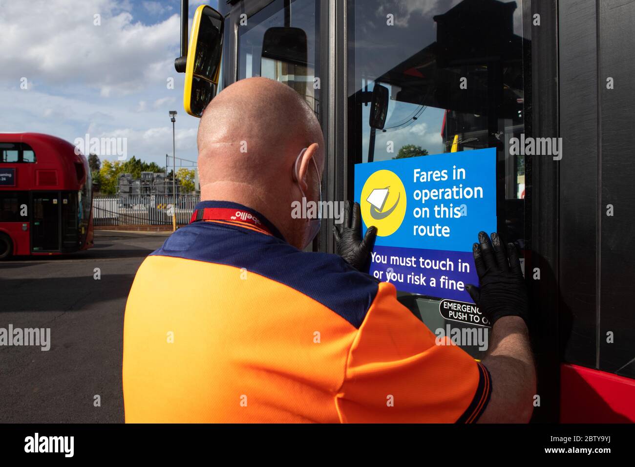 Busmitarbeiter installieren Aufkleber auf einem Bus in der Twickenham Busgarage, um Kunden daran zu erinnern, dass die Fahrpreise auf der Strecke während der COVID-19 pandemi in Betrieb sind Stockfoto
