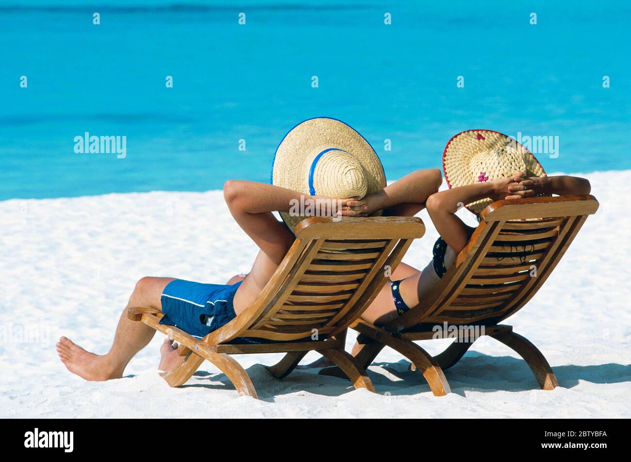 Pärchen liegen in Liegestühlen am Strand, auf den Malediven, im Indischen Ozean, Asien Stockfoto