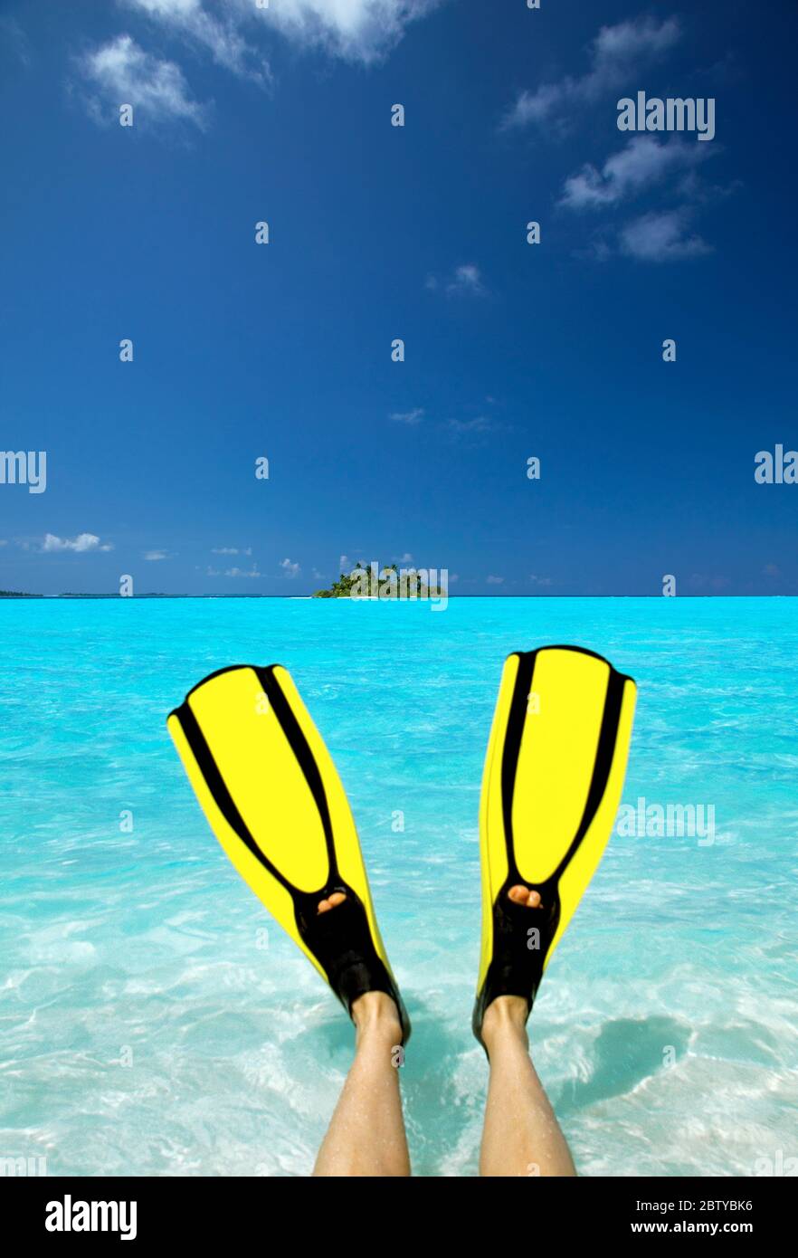 Tropische Insel und Person, die Flossen trägt, die im Meer, auf den Malediven, im Indischen Ozean, in Asien sitzen Stockfoto
