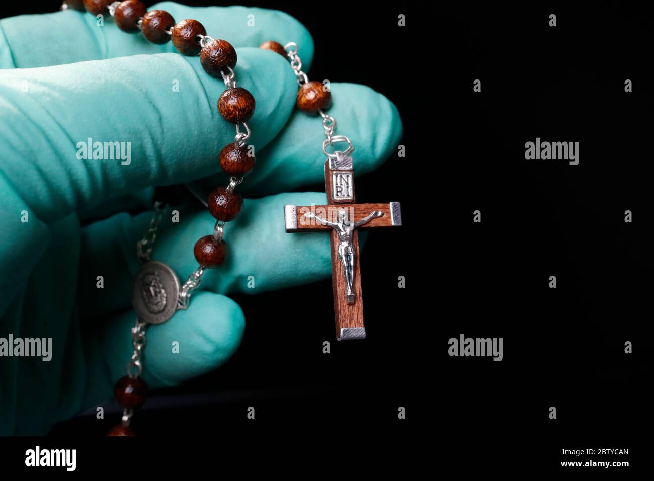 Coronavirus (COVID-19) Epidemie, christliche Rosenkranz mit Schutzhandschuh beten, Frankreich, Europa Stockfoto