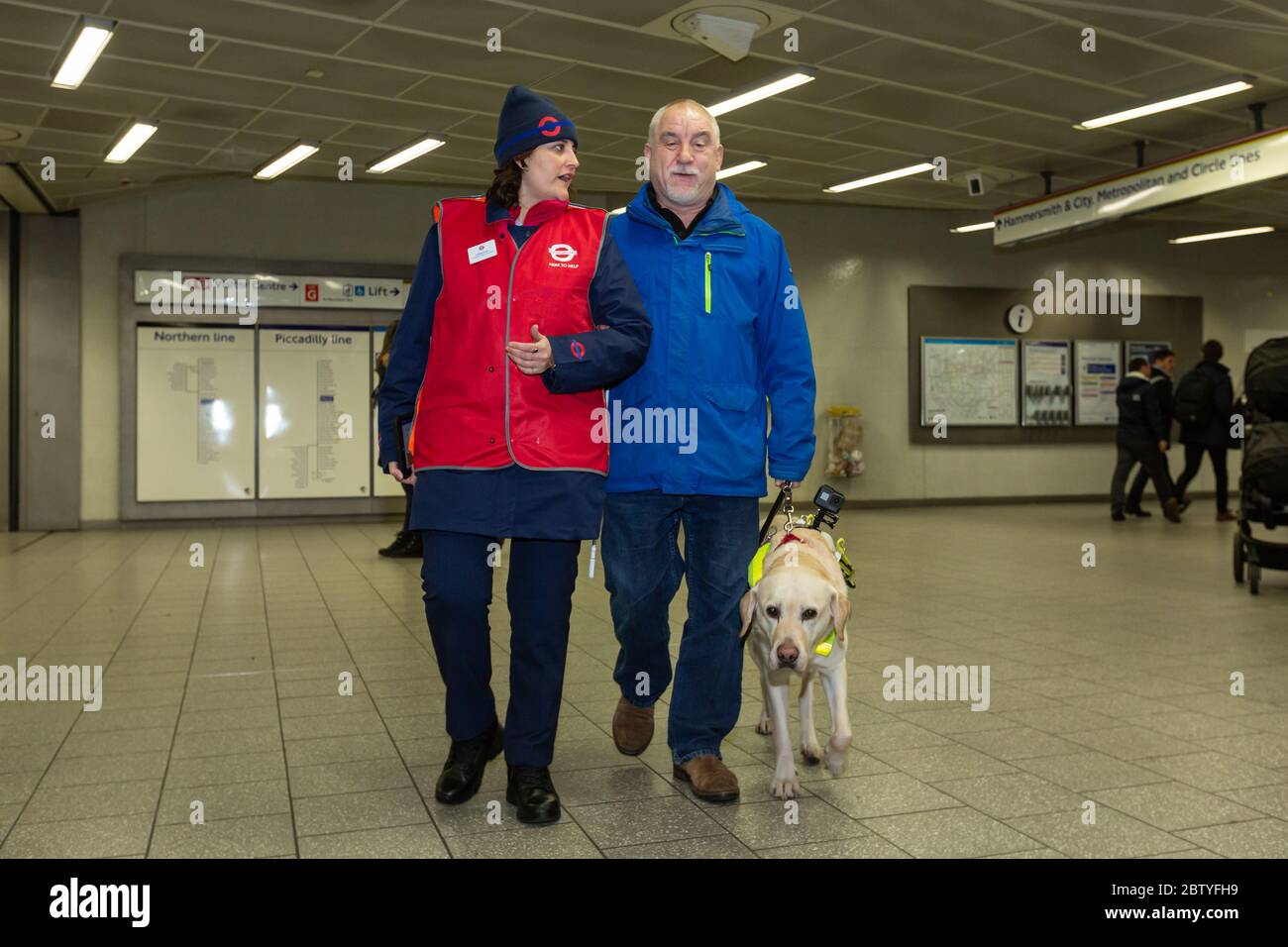 CSA gibt Hilfe für einen Guide Dog Benutzer in King's Cross St Pancras Stockfoto