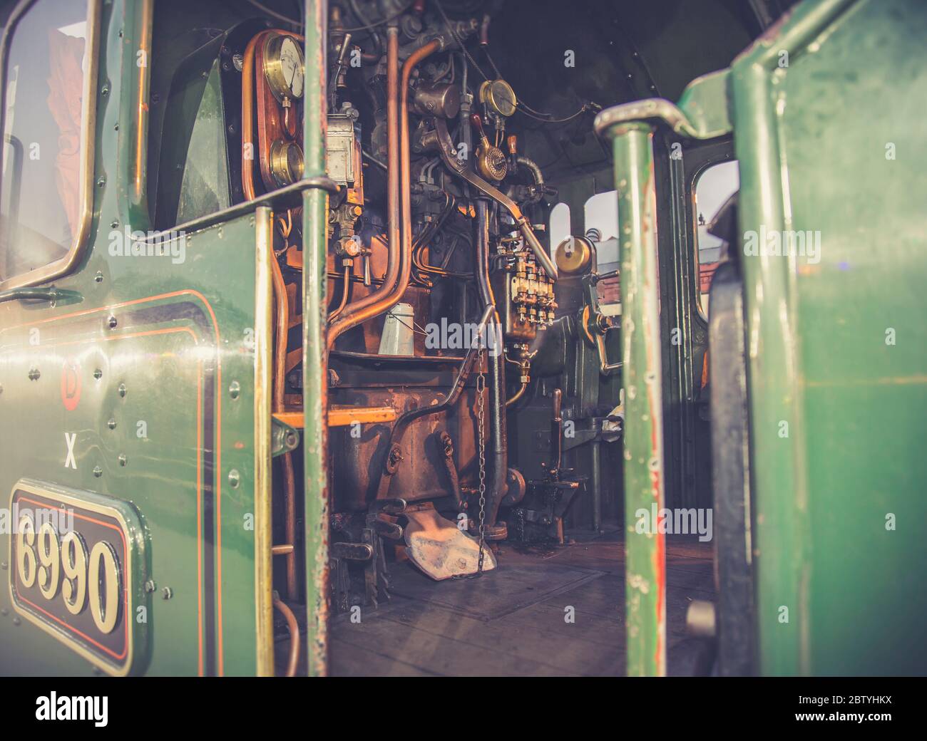 Atmosphärisch, Nahaufnahme der Zugfahrer-Bedienelemente, auf Fußplatte im Inneren Vintage UK Dampflokomotive Kabine bei Abend Wintersonne. Fahren mit Oldtimer-Zügen. Stockfoto