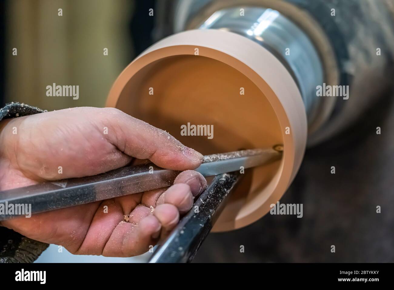 Der Zimmermann rasiert die Holzschale. Drehendes Holzrad. Schnitzerei innen bilden ein rundes Detail. Tischler verwendet Metallwerkzeug, um die handgemachte zu machen Stockfoto