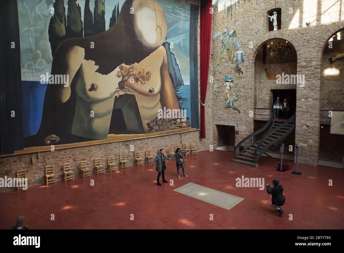 Die Besucher fotografieren neben dem unmarkierten Grab des spanischen surrealistischen Malers Salvador Dalí in der Haupthalle des Salvador Dalí Theaters und Museums in Figueres, Katalonien, Spanien. Im Hintergrund ist die riesige Kulisse zu sehen, die Salvador Dalí für das Ballett Labyrinth (1941) entworfen hat. Stockfoto