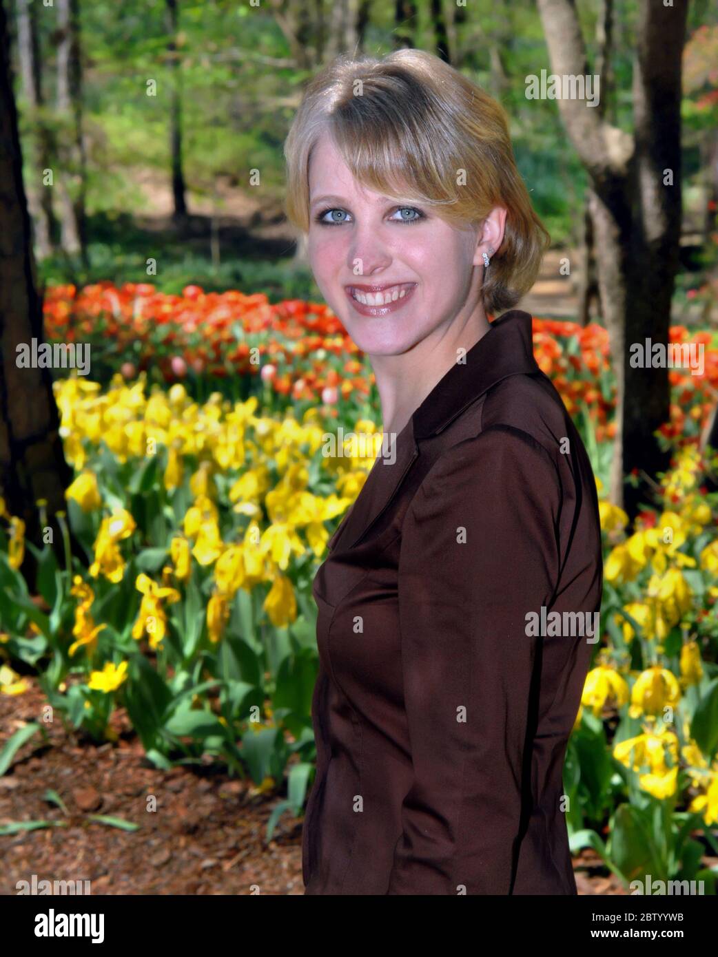 Schöne junge Frau erkundet die Tulpen im Garvan Woodland Garden in Hot Springs, Arkansas. Sie lächelt und ist glücklich. Stockfoto