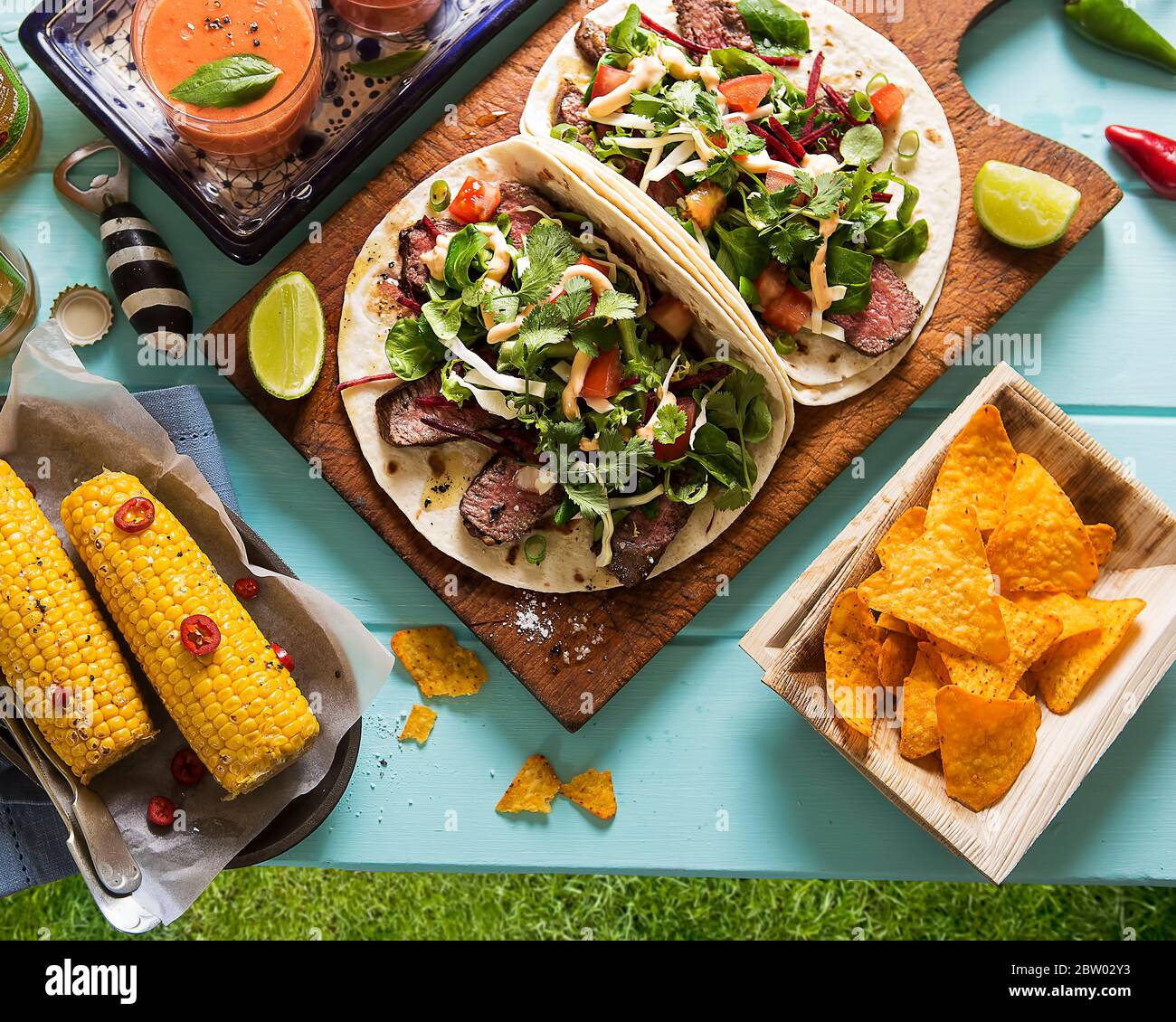 Fiesta Mexicana! Mexikanische Fiesta im Freien: Tortilla Chips, Rindfleisch Enchiladas mit Salat, mexikanischer Mais mit roten Chili Paprika, Gazpacho-Suppe Stockfoto