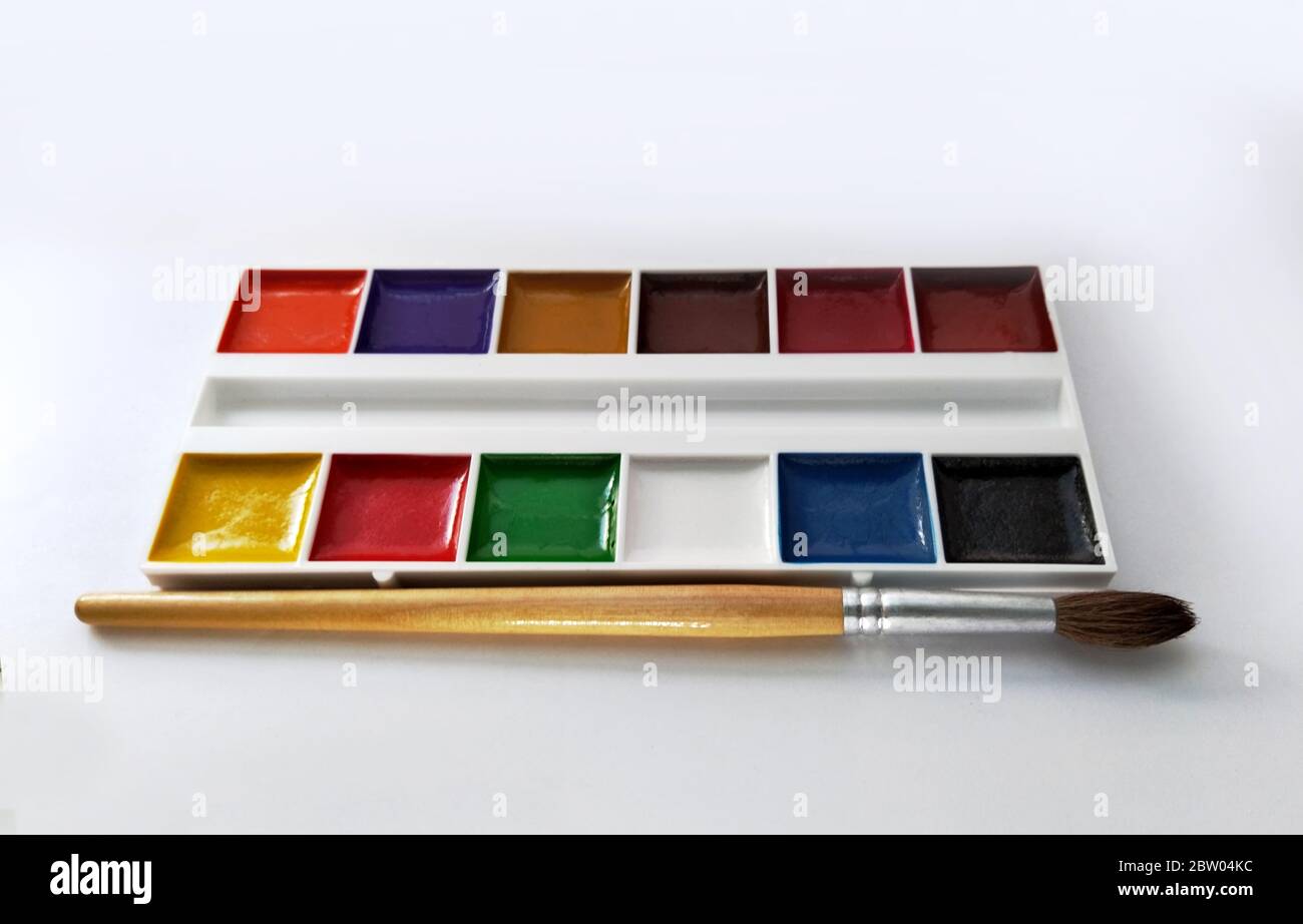 Satz von Aquarellfarben in einem weißen Behälter. Farbe und Pinsel isoliert auf weißem Hintergrund Stockfoto