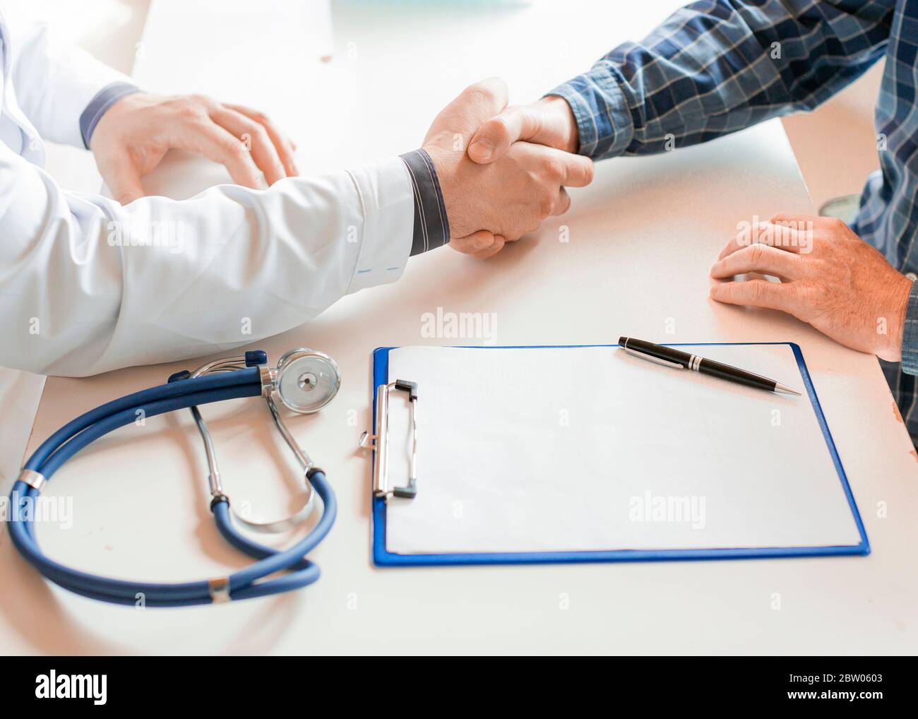 Patient und Arzt schütteln die Hände nach Unterzeichnung eines Krankenversicherungsvertrags. Konzept Der Gesundheitspflege. Stockfoto