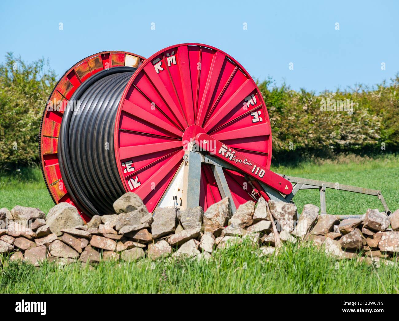 Große Wasserkabeltrommel im Erntefeld zur Bewässerung von Pflanzen bei trockenem Wetter, East Lothian, Schottland, Großbritannien Stockfoto