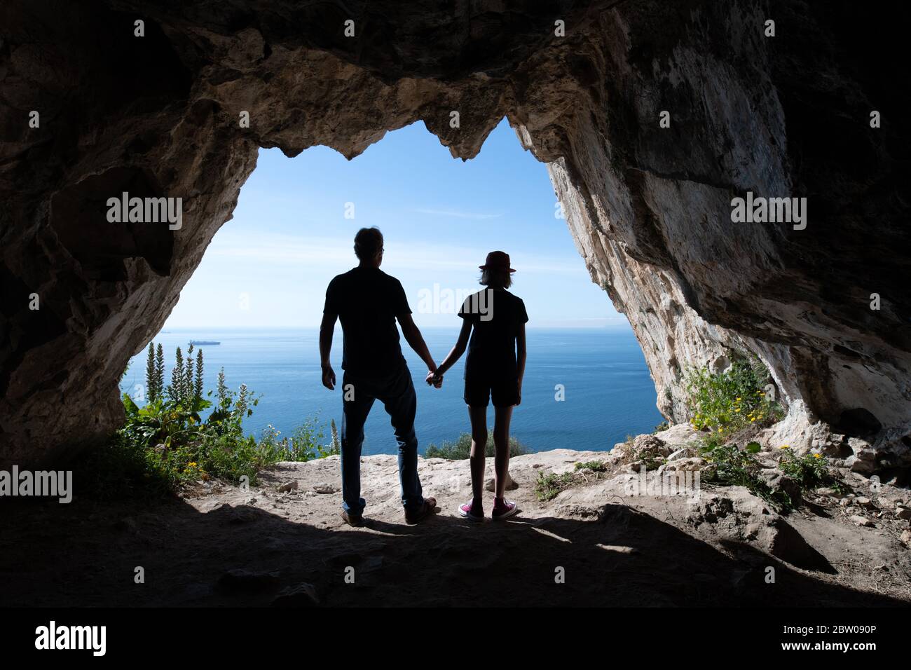 Silhouetten von Touristen stehen im Eingang einer Höhle Stockfoto