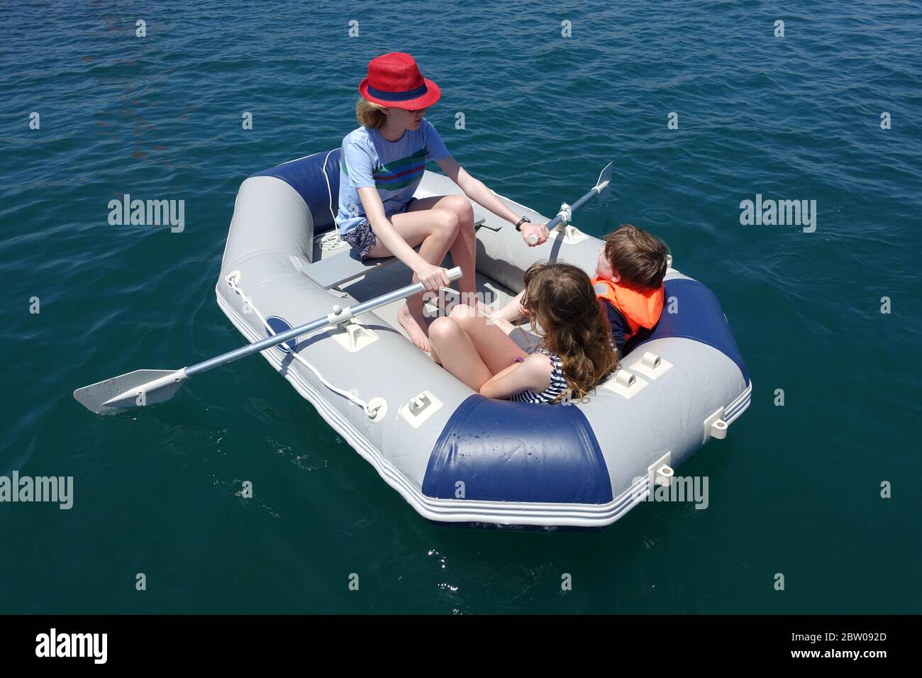 Drei Kinder haben Spaß in einem Schlauchboot Stockfoto