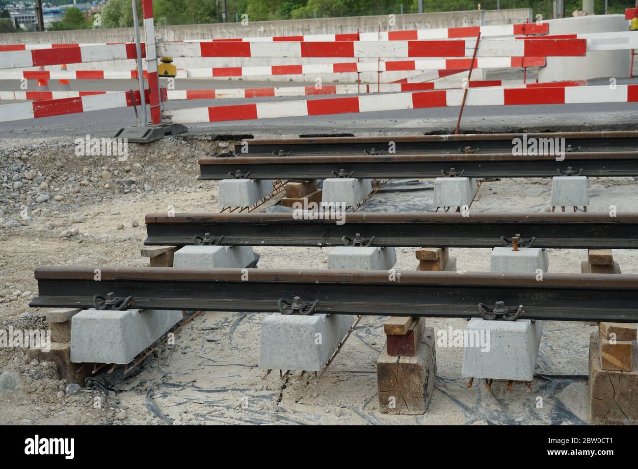 Schienen für die Straßenbahn bereit, auf einer Tiefbau-Baustelle installiert werden, Bau Straßenbahnlinie mit roten und weißen Barriere Planken. Stockfoto