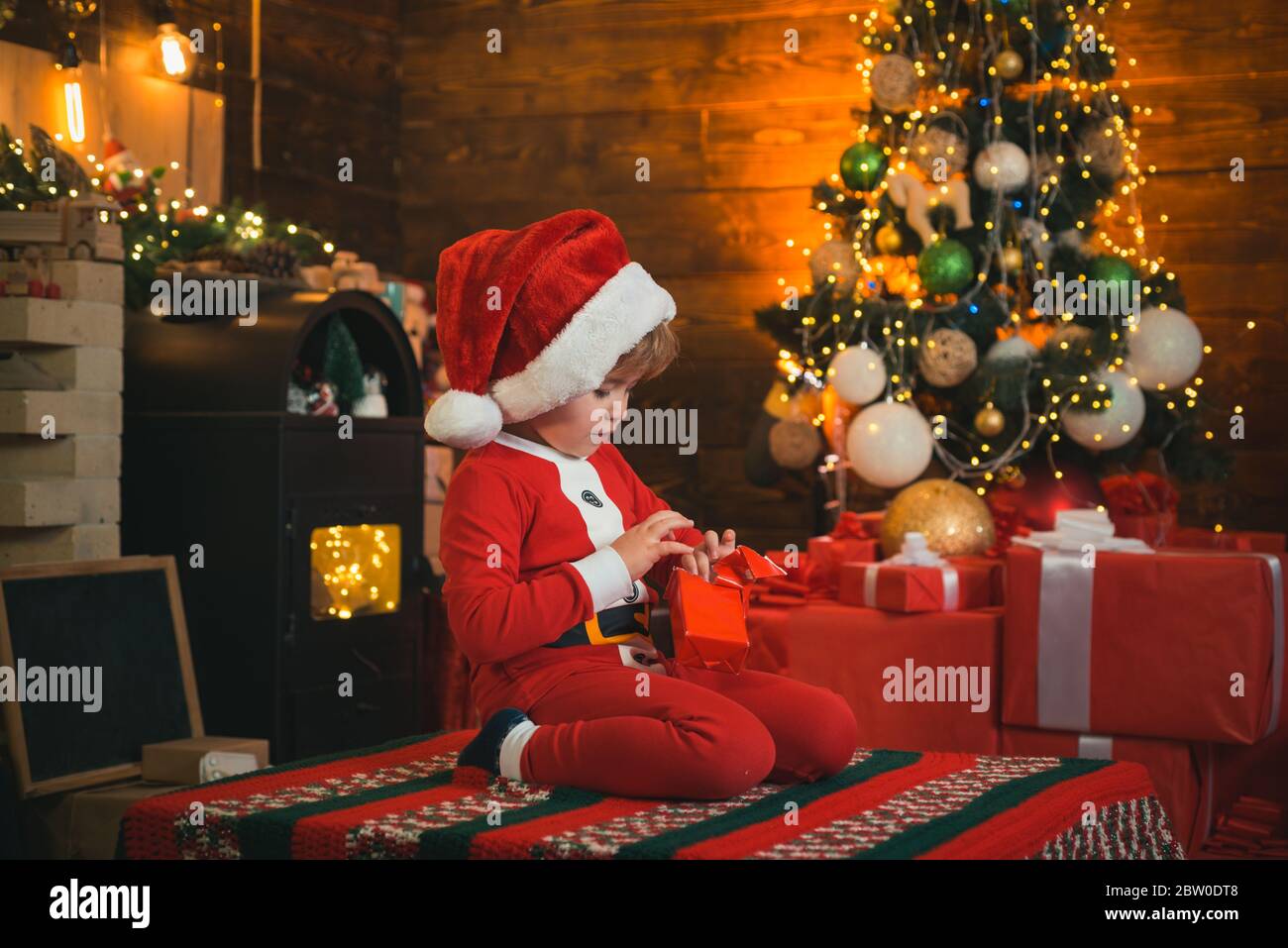 Kleiner Weihnachtsmann Helfer Elfe mit einem magischen Geschenk für Weihnachten. Weihnachten. Santa, kleiner Helfer. Ein glückliches Familienkonzept. Wenig Genie. Kleiner Junge in Sant Stockfoto