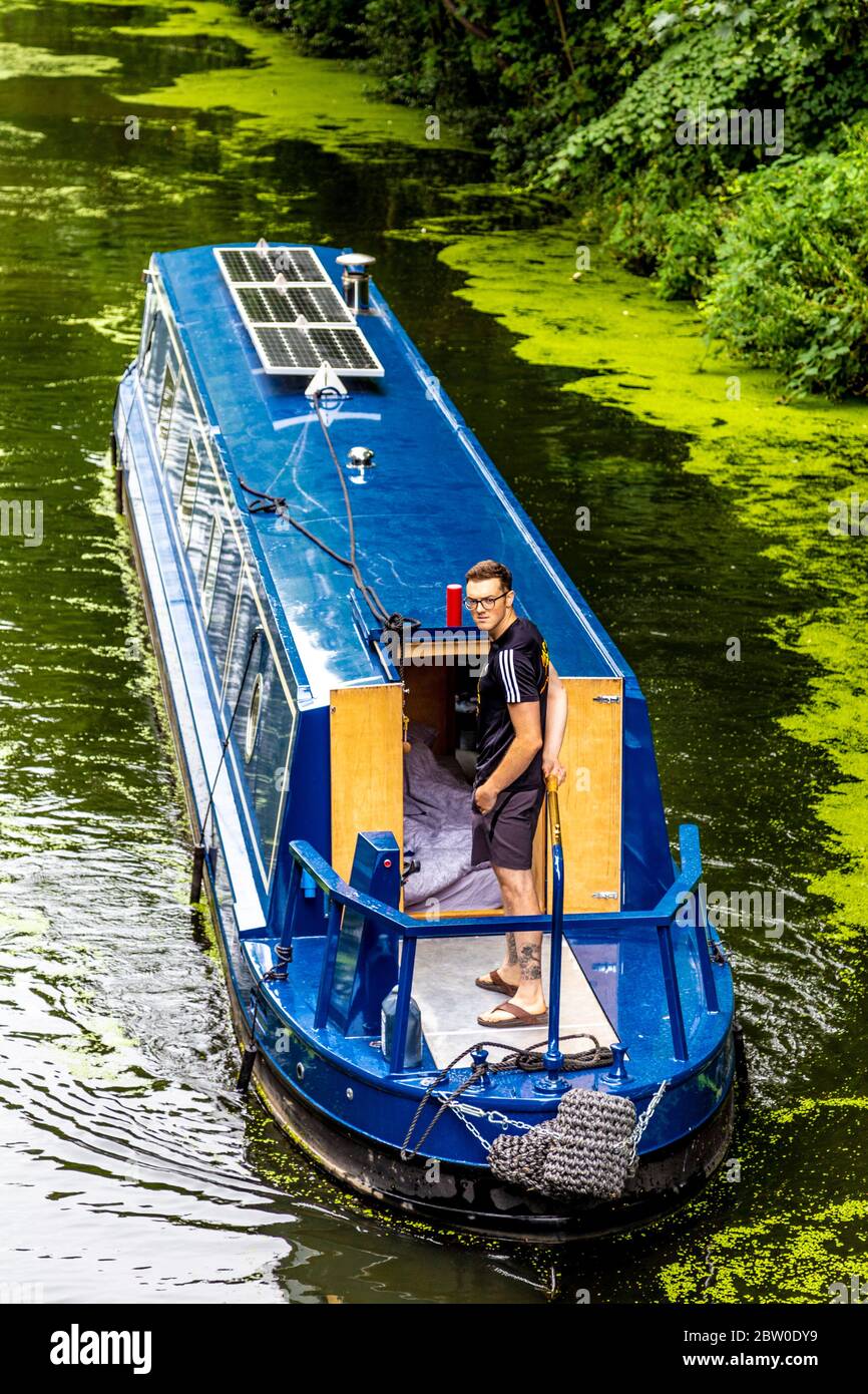 Mann, der einen Lastkahn auf dem Regent's Canal, London, Großbritannien steuert Stockfoto