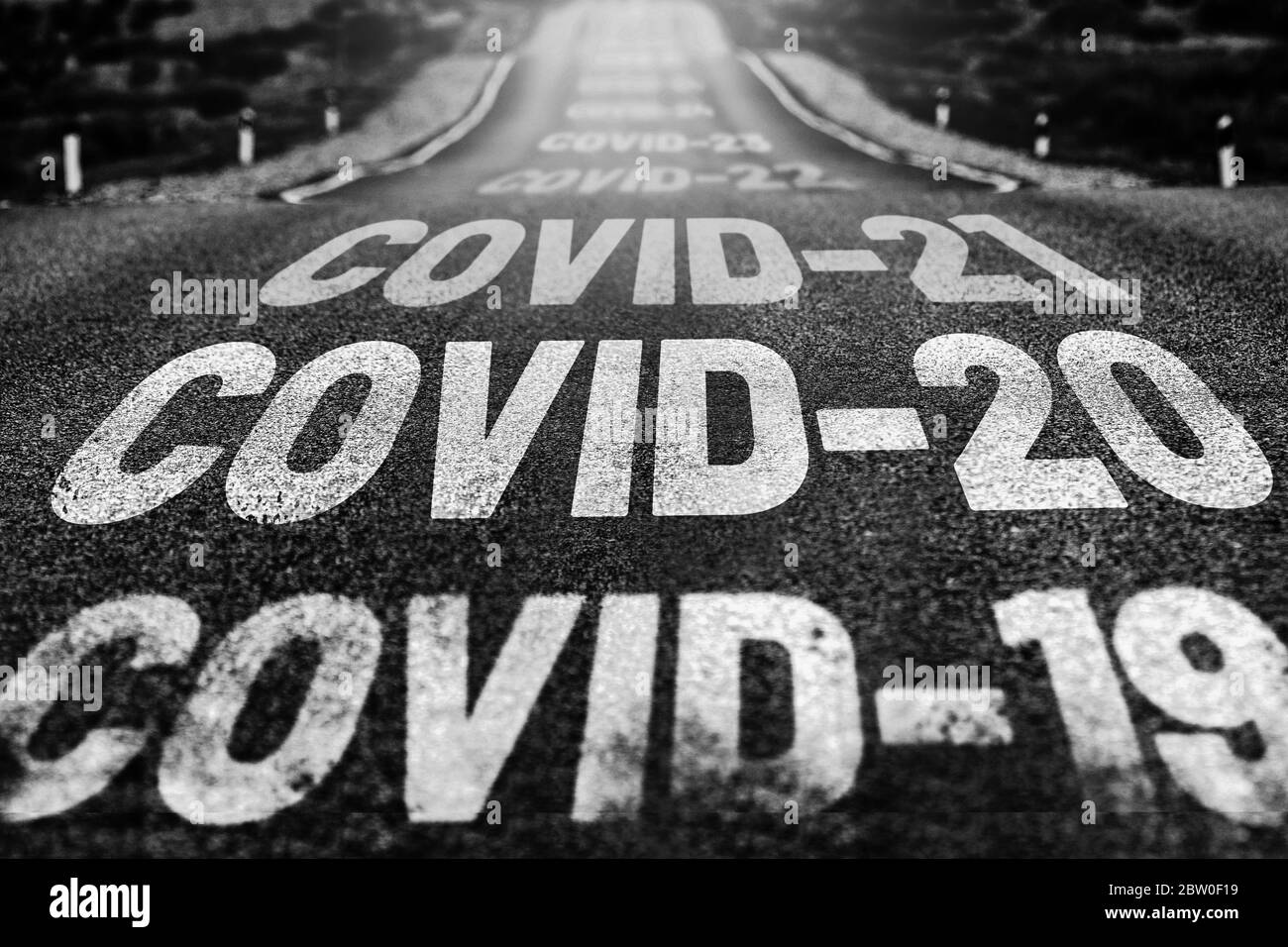 Verlassene Autobahn mit dem Text COVID-19, COVID-20, COVID-21 und so weiter. Das Konzept der neuen Weltpandemien. Schwarz-weißer Hintergrund Stockfoto