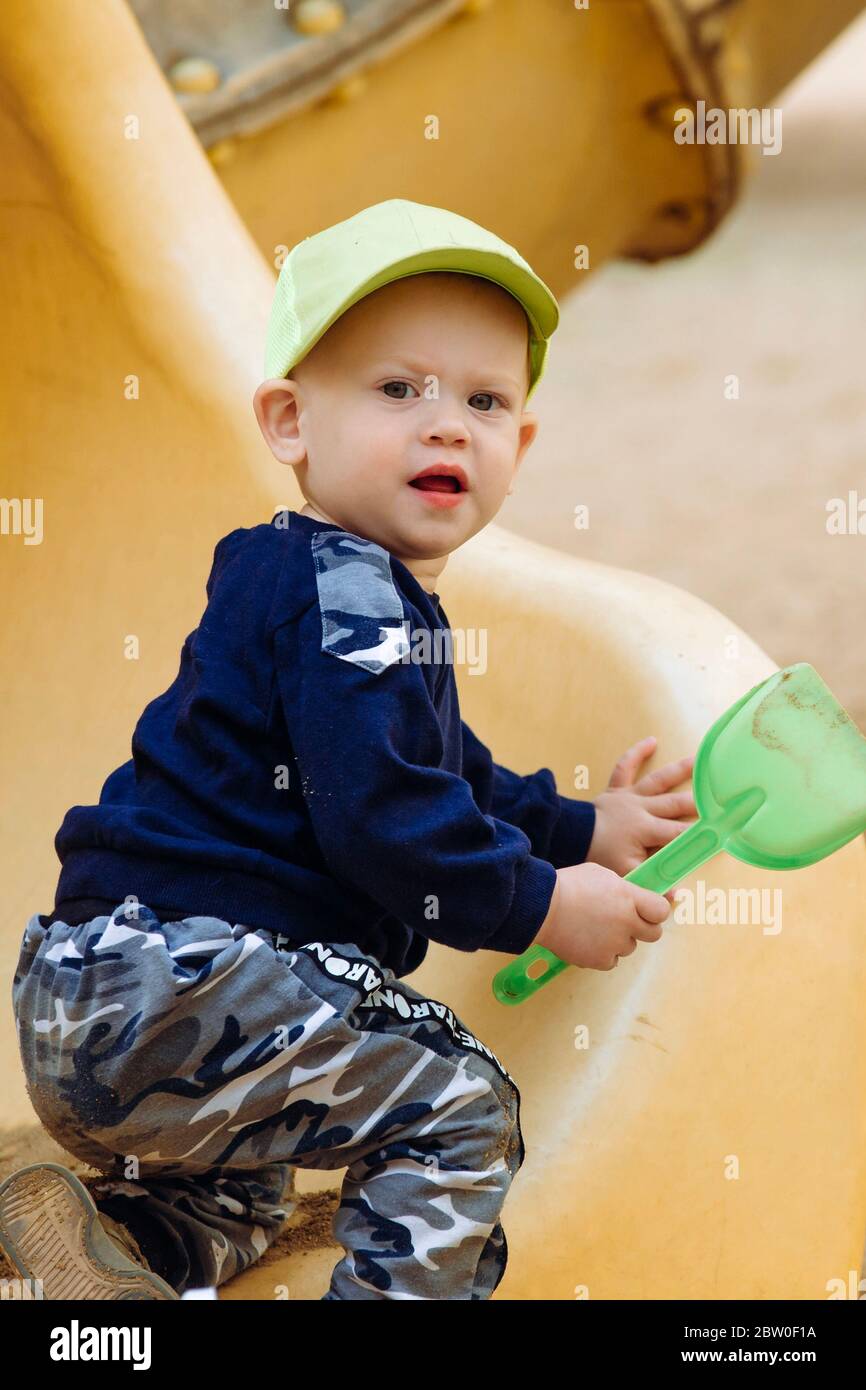 Ein Junge 1-2 Jahre alt mit einer Schaufel in den Händen spielt auf dem Spielplatz Stockfoto