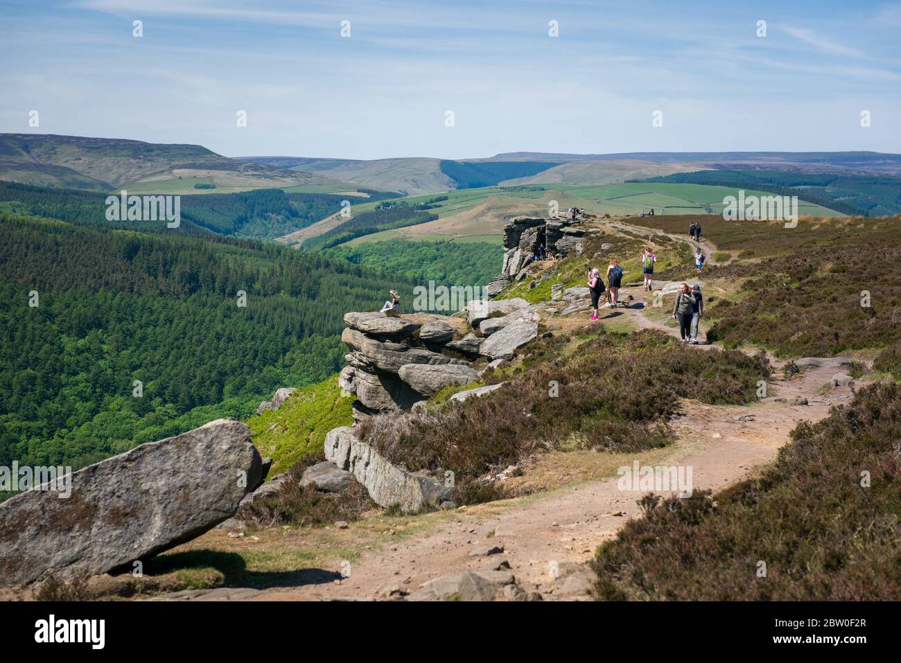 Blick von Bamford Edge in Richtung Ladybower Reservoir mit Menschen sitzen / klettern / genießen den Tag nach der Sperrung Coronavirus erleichtert wurde Stockfoto