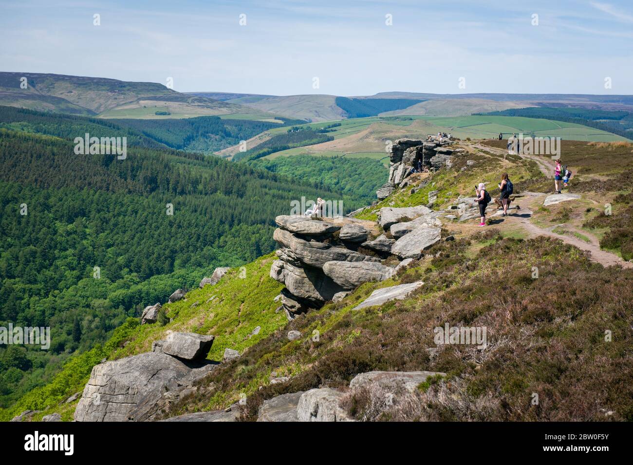Blick von Bamford Edge in Richtung Ladybower Reservoir mit Menschen sitzen / klettern / genießen den Tag nach der Sperrung Coronavirus erleichtert wurde Stockfoto