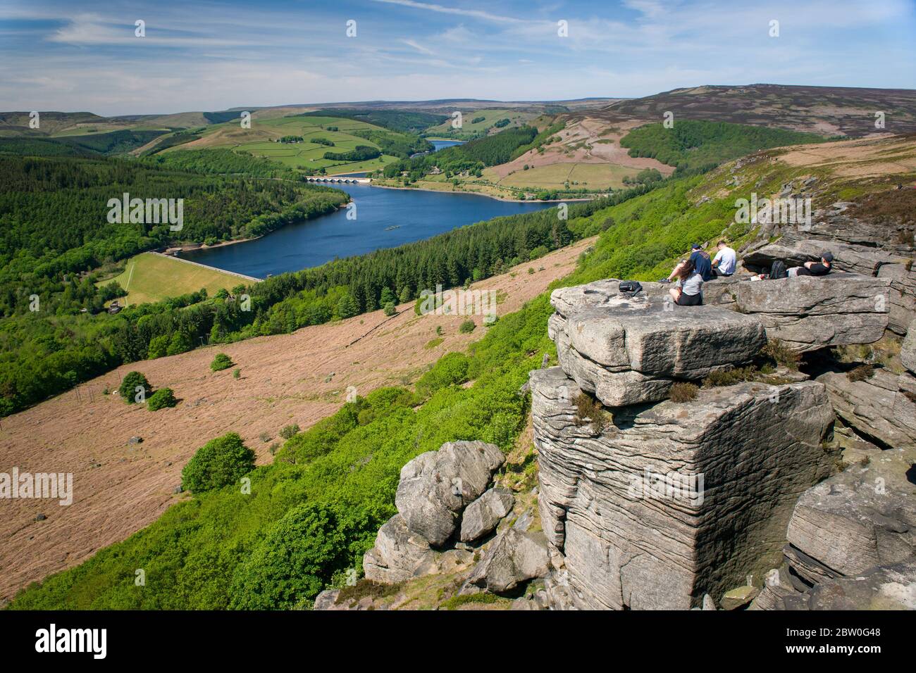 Blick von Bamford Edge in Richtung Ladybower Reservoir mit Menschen sitzen / klettern / genießen den Tag nach der Sperrung Coronavirus erleichtert wurde Stockfoto