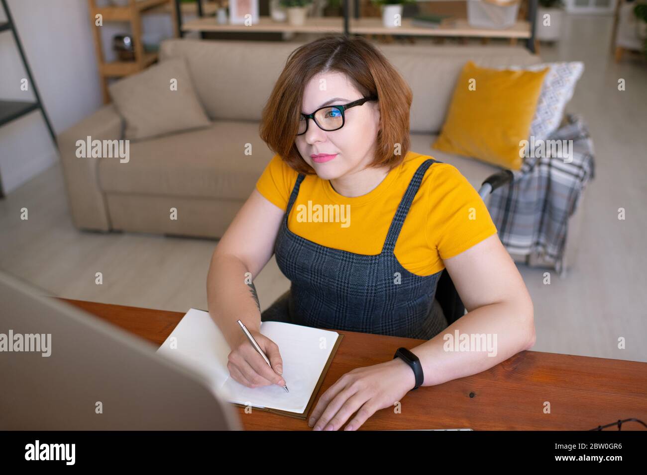 Konzentrierte behinderte Student Mädchen in Brille Schreiben Sie Vorlesung während Online-Kurs auf dem Computer Stockfoto