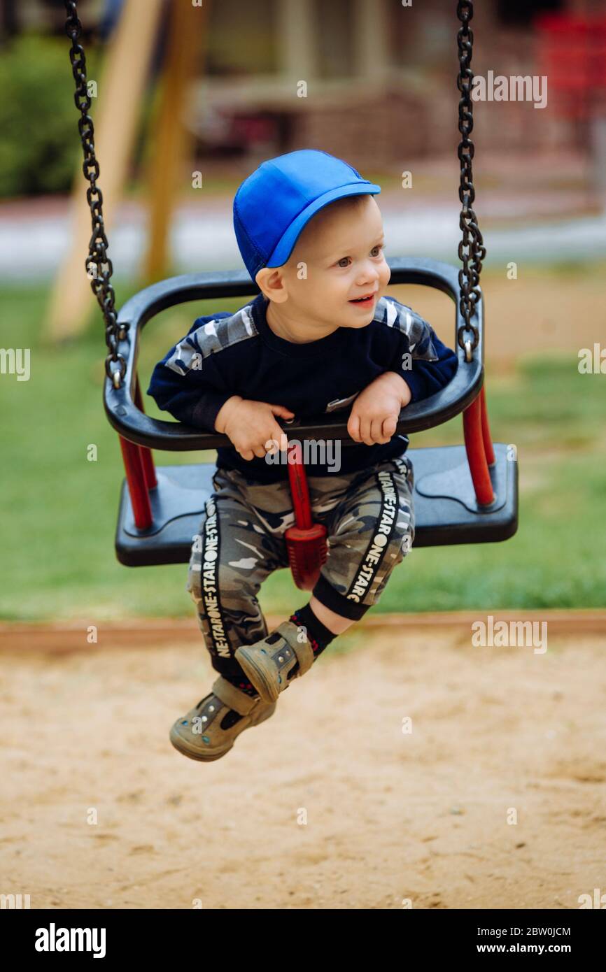 Schöner Junge 1-2 Jahre alt, auf einer Schaukel, Spielplatz, Nahaufnahme Stockfoto