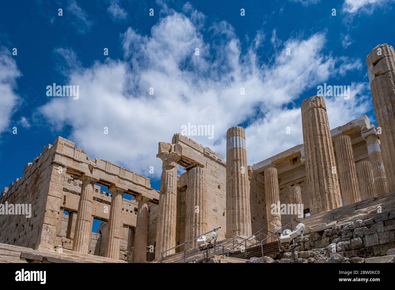Akropolis von Athen, Griechenland Wahrzeichen. Propylaea Eingangstor leer, Altgriechisch Säulen und Treppen, niedrige Winkel Blick, blau bewölkten Himmel. Stockfoto